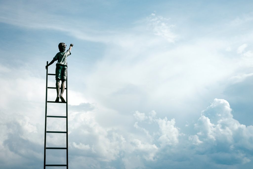 Boy reaching for the sky. Photo by Samuel Zeller on Unsplash